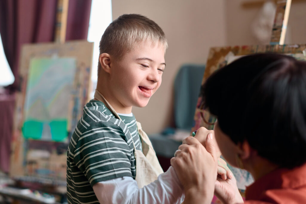 boy with down syndrome enjoying art class boy with down syndrome enjoying art class