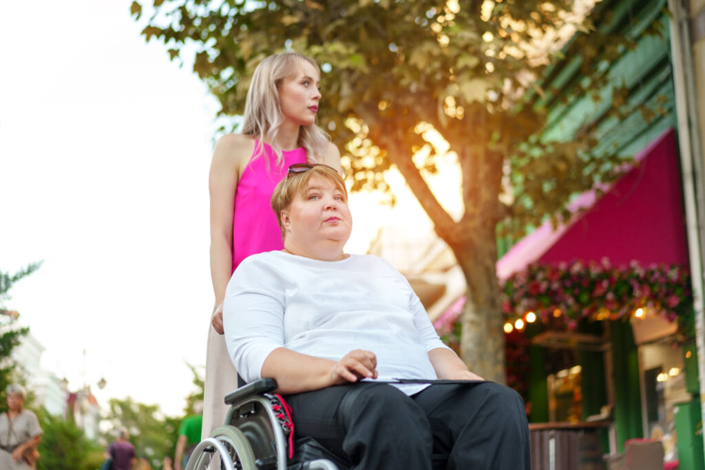 young woman helping mature woman in wheelchair in the city young woman helping mature woman in wheelchair in the city
